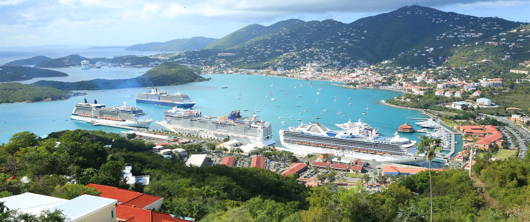Several cruise ships docked in a hilly Caribbean island harbor